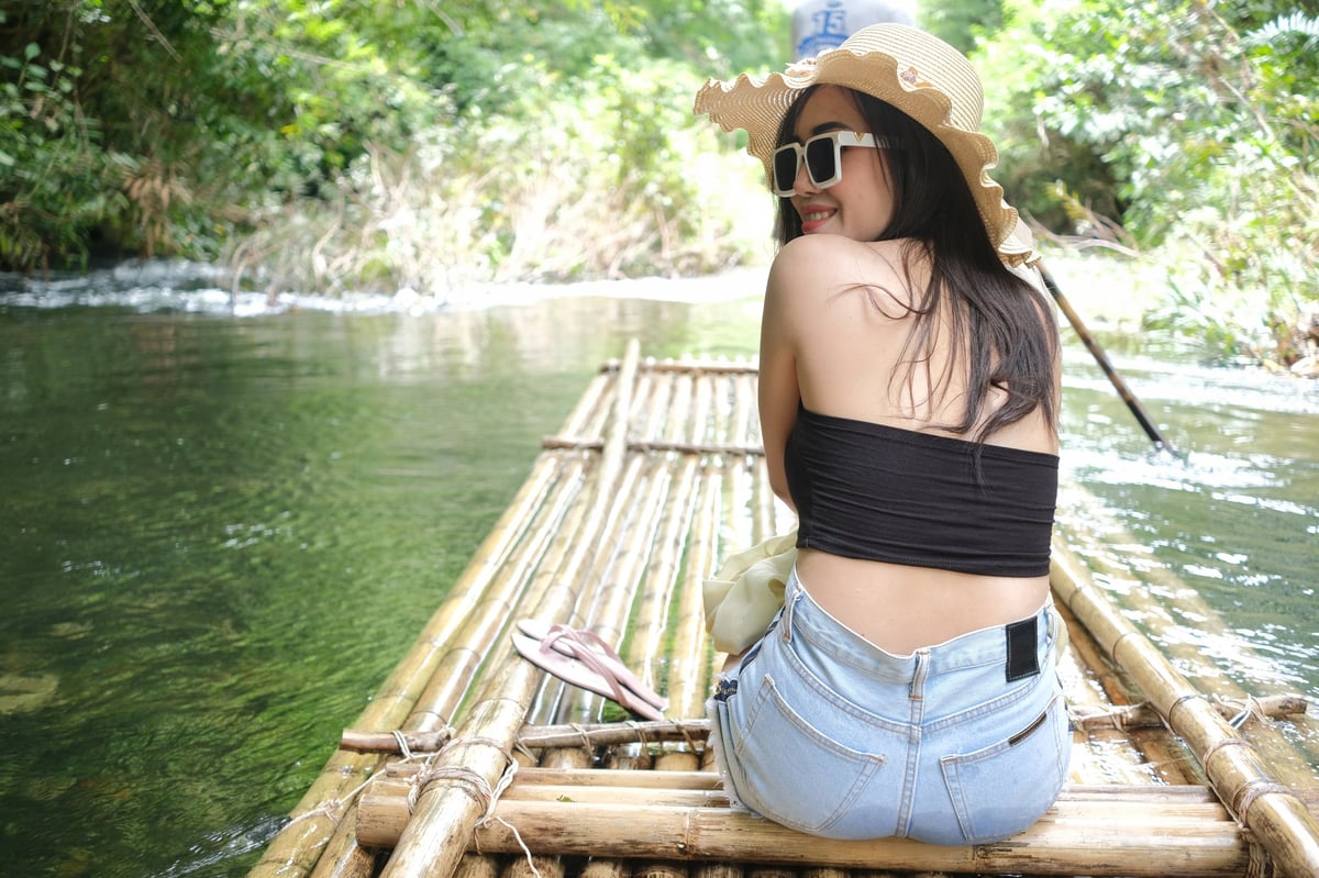 A traveler relaxing on a bamboo raft drifting down a calm tropical river