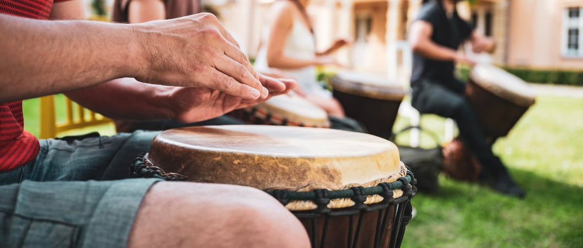 A man playing a traditional hand drum outdoors during a cultural Rastafari community experience