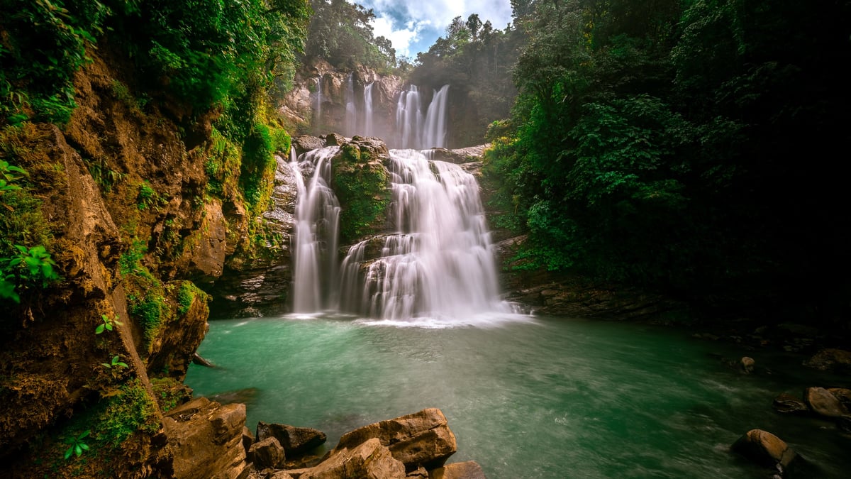 Lush tropical waterfall cascading into a swimmable emerald pool, like YS Falls in St Elizabeth