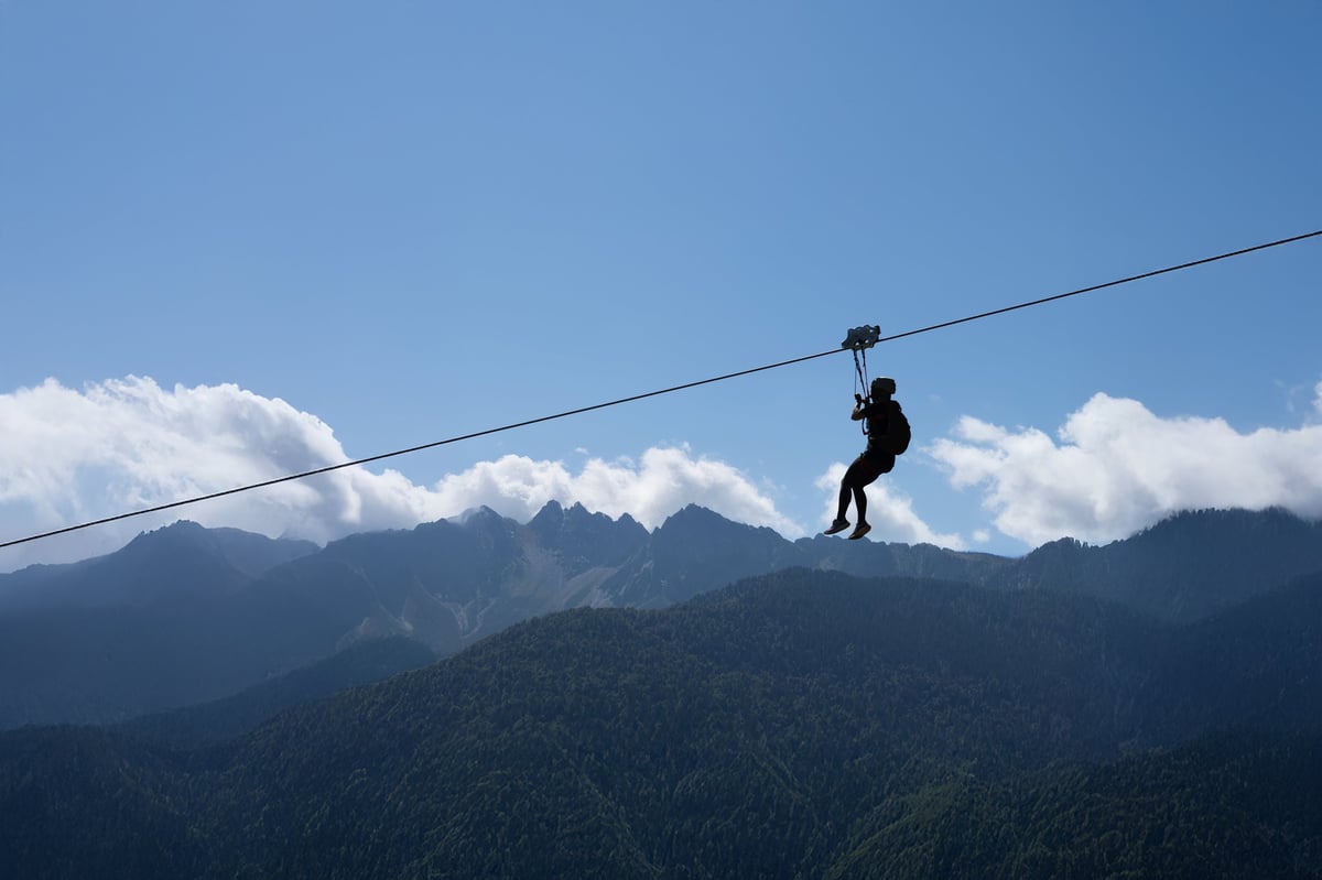 A person ziplining through lush green forest canopy