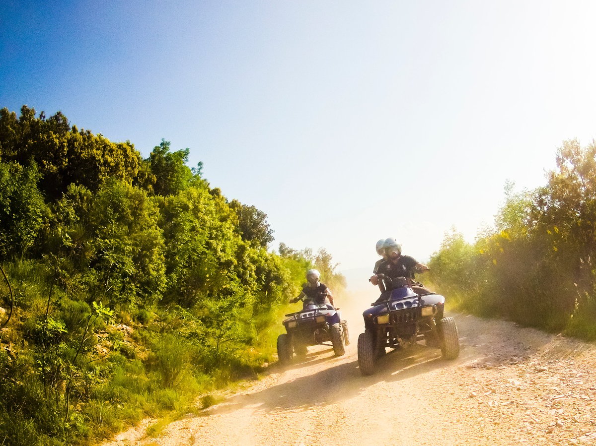 Two riders on quad bikes driving through a lush jungle trail on their Jamaican adventure